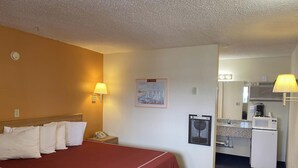 Habitación de hotel con cama, lámparas de noche, una pequeña mesa de escritorio con microondas y un cuadro en la pared.