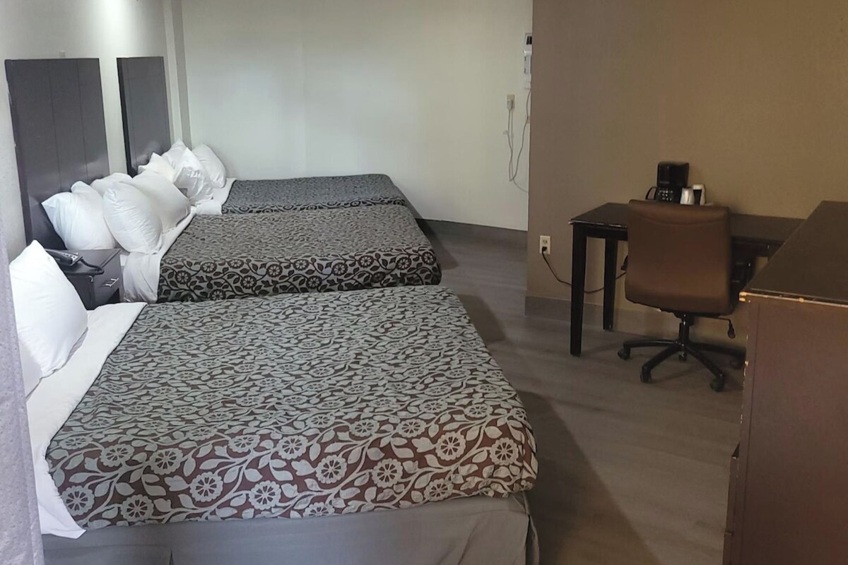 Ein Hotelzimmer mit zwei Betten, einem Schreibtisch, einem Stuhl und einem Kleiderschrank.