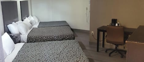 A hotel room with two beds, a desk, a chair, and a wardrobe.