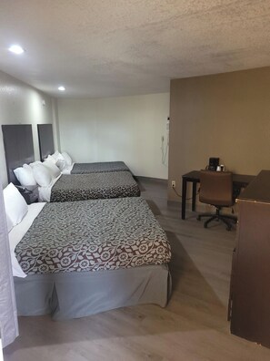 Ein Hotelzimmer mit zwei Betten, einem Schreibtisch, einem Stuhl und einem Kleiderschrank.