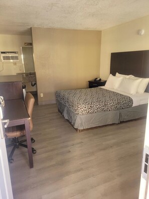 Een hotelkamer met een bed, een bureau, een stoel, een nachtkastje en een badkamer.