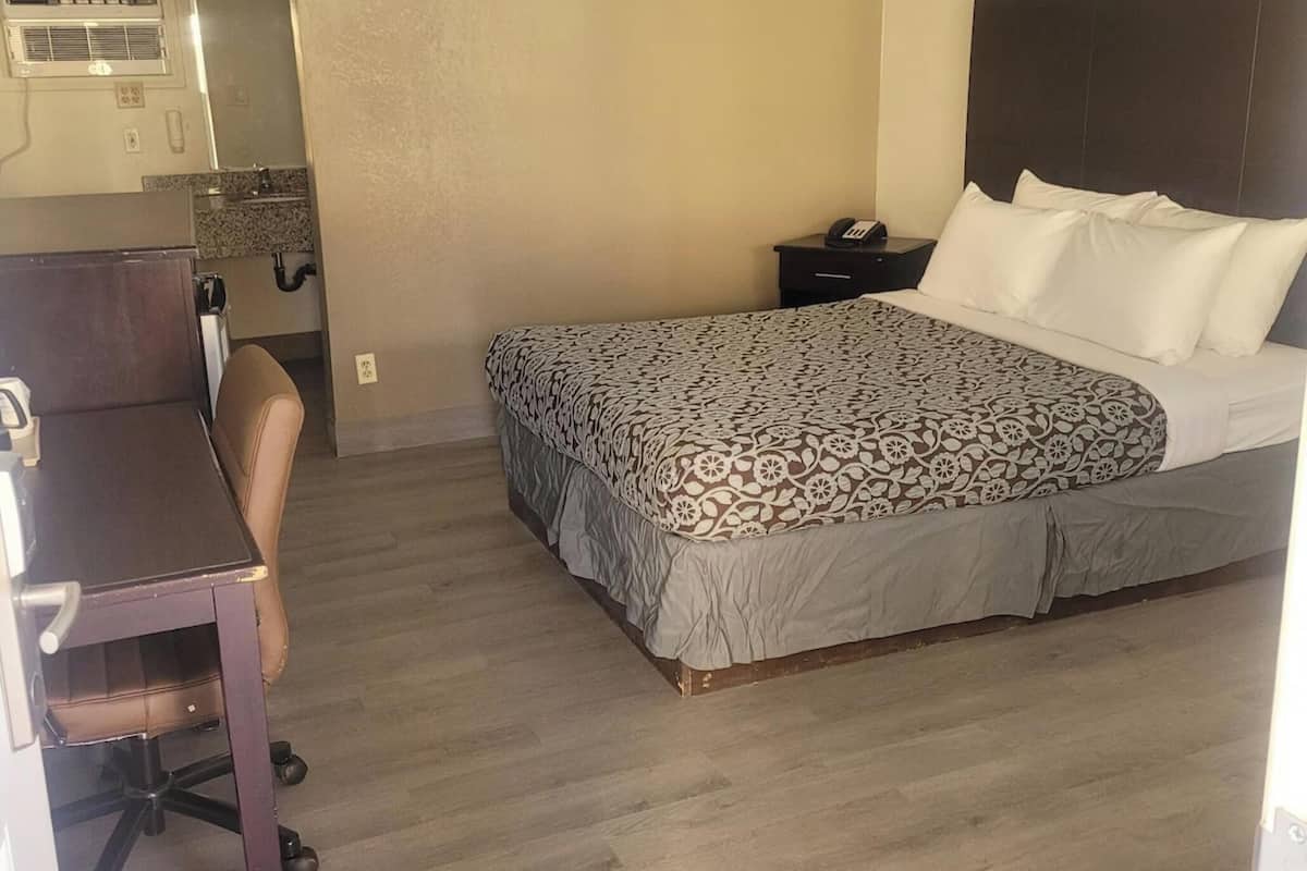 Une chambre d’hôtel comprenant un lit, un bureau, une chaise, une table de chevet et une salle de bain.