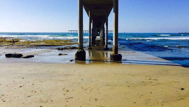 Ein Strand mit einem Steg, der sich ins Meer erstreckt.