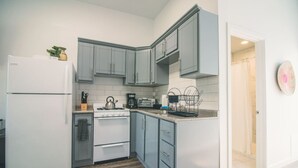 Eine moderne Küche mit grauen Schränken, einem weißen Kühlschrank und Holzboden.