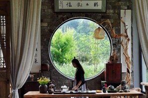 Una habitación con un amplio ventanal circular, una mesa de madera con juego de té y decoración tradicional.