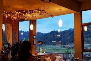A room with large windows, a wooden ceiling, and hanging lights.