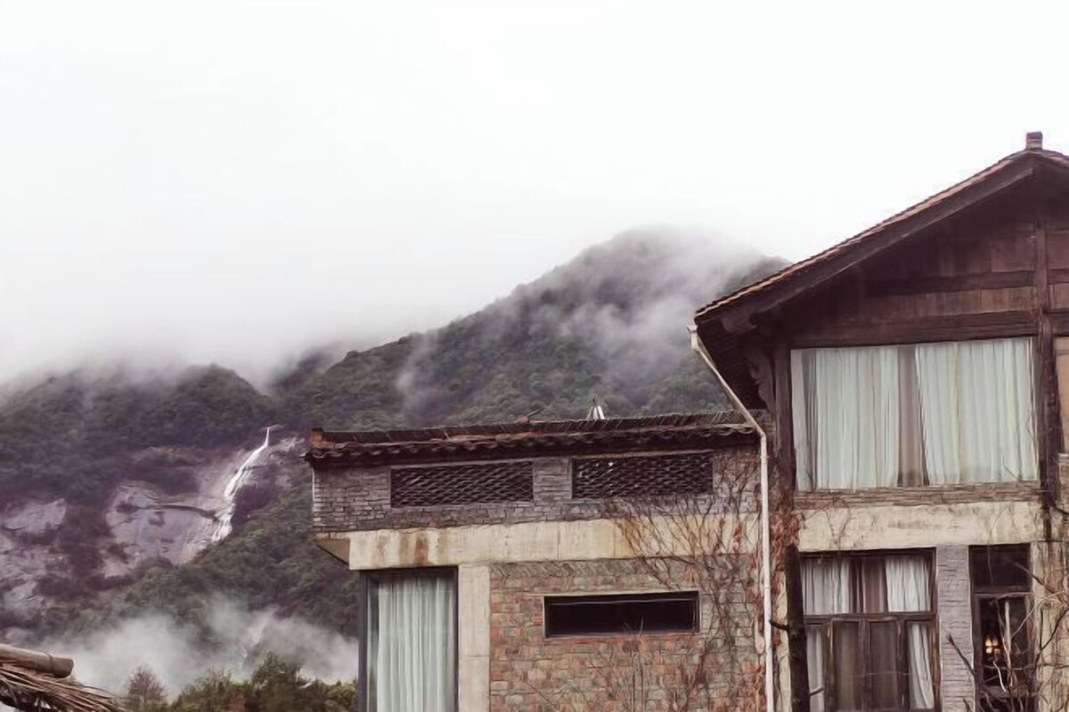 Un edificio rústico con fachada de piedra, ventanas grandes y techo de madera.