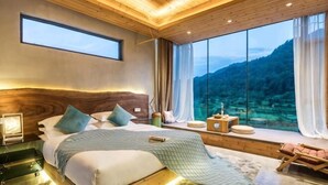 Ein Schlafzimmer mit einem großen Bett, Blick auf die Berge, Holzbalkendecke und einem Fenster mit Vorhängen.