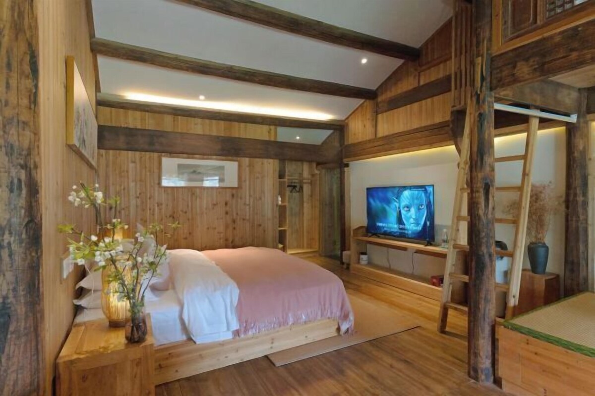 Una habitación de madera con una cama, un televisor y una escalera.