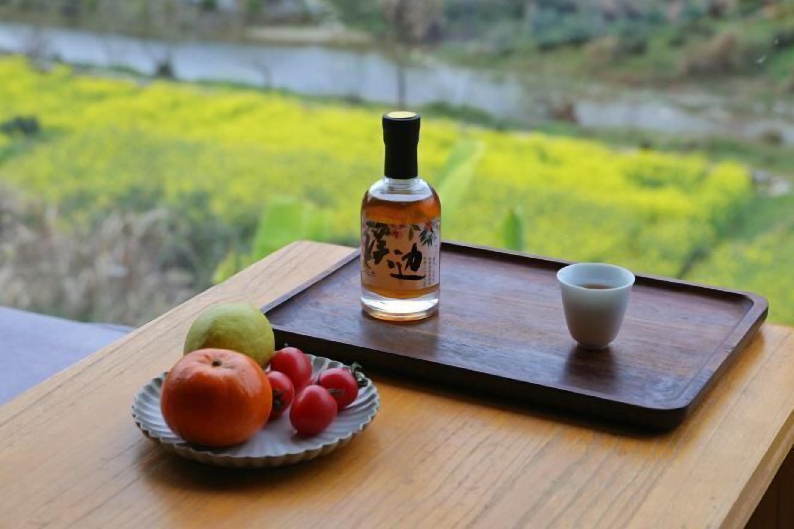 A tray with a bottle, a cup, and a plate with fruit.