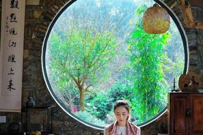 Une pièce dotée d’une grande fenêtre circulaire, d’un meuble en bois et d’un luminaire suspendu.