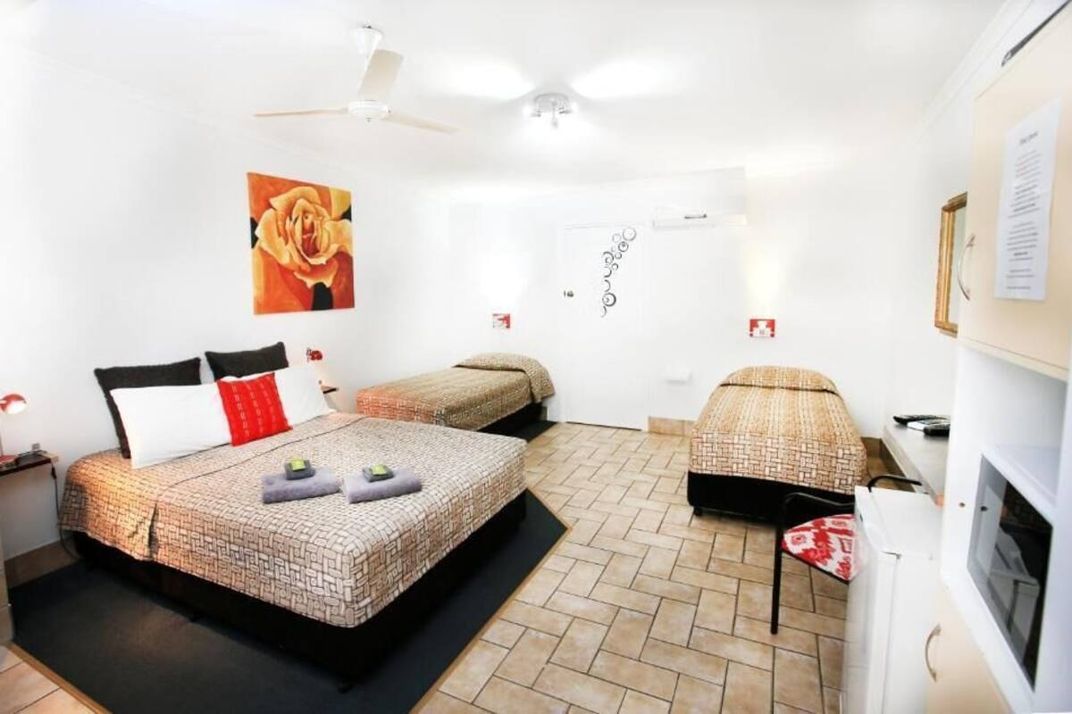 Een slaapkamer met twee bedden, een plafondventilator, een tv aan de muur en een klein tafeltje.