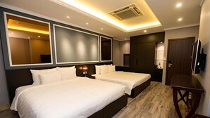 Een hotelkamer met twee bedden, een houten vloer, een grote spiegel en een televisie.