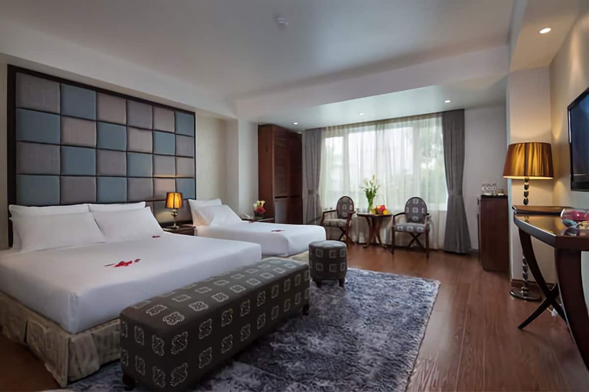 Ein Hotelzimmer mit zwei Betten, einem Schreibtisch, einem Stuhl und einem Fernseher.