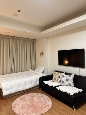 Relax in a serene bedroom with a large bed, sofa, and flat-screen TV.