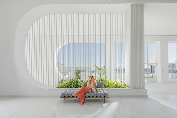 Un intérieur moderne avec une grande fenêtre, un banc et des plantes d’intérieur.