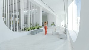 A modern interior with a curved white wall, a seating area with a white sofa, and a plant arrangement. - White Hills Resort - Posh Club (Sharm El Sheikh)
