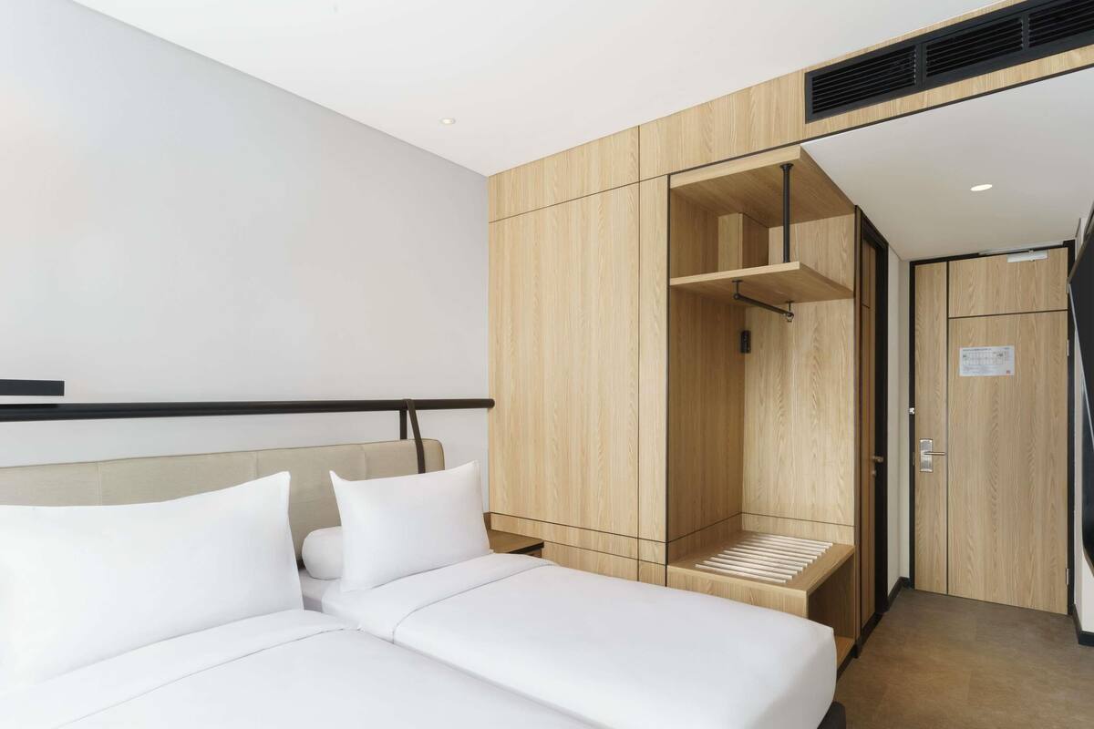 Una habitación de hotel moderna con una cama, un armario de madera y un banco empotrado.