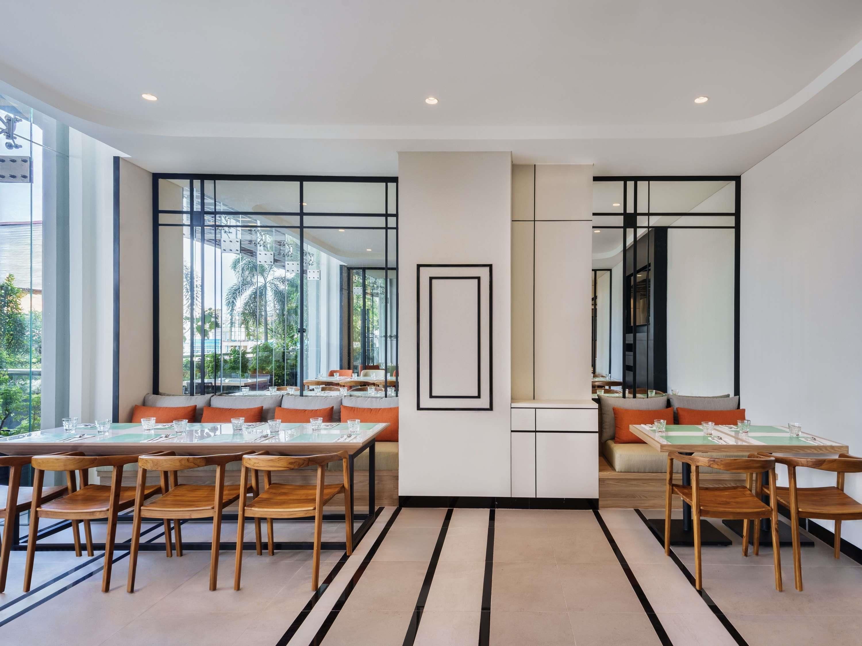 A modern dining area with glass partitions, wooden chairs, and a central white column.
