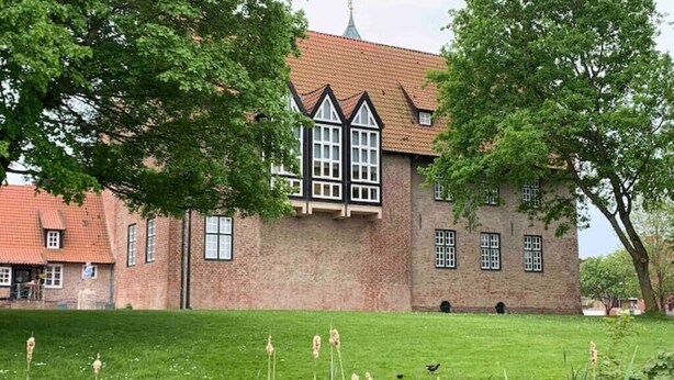 Un bâtiment traditionnel en briques, doté d’un toit à forte pente et de fenêtres à cadre blanc.