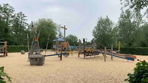 Un terrain de jeux équipé de divers appareils, notamment des balançoires, des toboggans et des structures d’escalade.