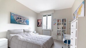 A bedroom with a bed, a bookshelf, a radiator, and a window. - Tommaso Apartment with free parking (Firenze)