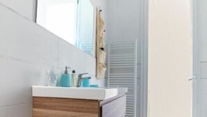 A modern bathroom with a wooden vanity, a large mirror, and a glass shower enclosure. - Tommaso Apartment with free parking (Firenze)