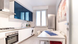 A compact kitchen with a stove, oven, sink, and a washing machine. - Tommaso Apartment with free parking (Firenze)
