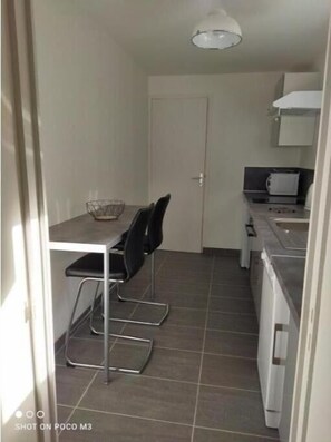 A compact kitchen with a dining table, chairs, a microwave, and a cabinet. - Joli T1 Hyper Centre Rochefort (Rochefort)