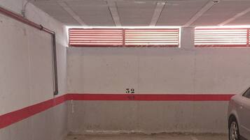 Een parkeergarage met betonnen vloeren, rode en witte wanden en een metalen barrière in het midden.