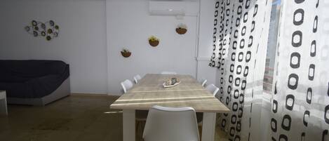 A dining area with a wooden table, white chairs, and a ceiling air conditioner.