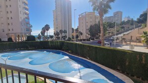 A swimming pool with a unique blue design, surrounded by tall residential buildings and palm trees.