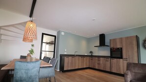 Una cocina moderna con armarios de madera, horno empotrado y una lámpara colgante.