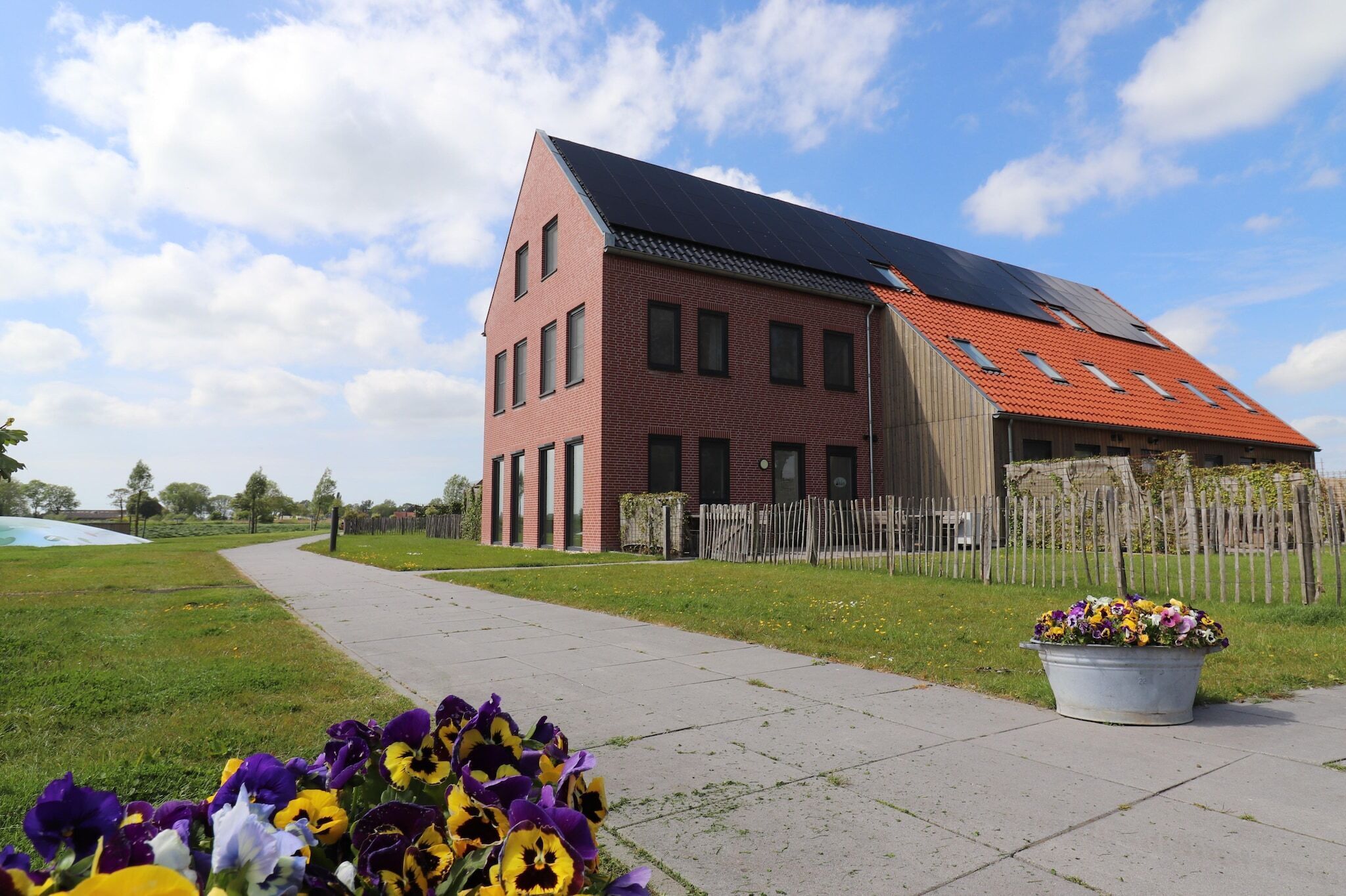 A modern building with a sloped roof, a paved pathway, and a flower bed.