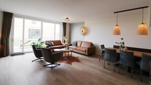 Una sala de estar moderna con sofá, sillas, una mesa de centro y una mesa de comedor.