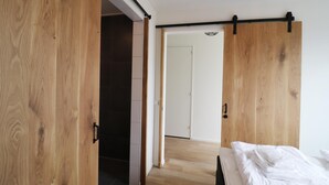Un dormitorio con un armario de madera, una cama y una puerta que da a otra habitación.