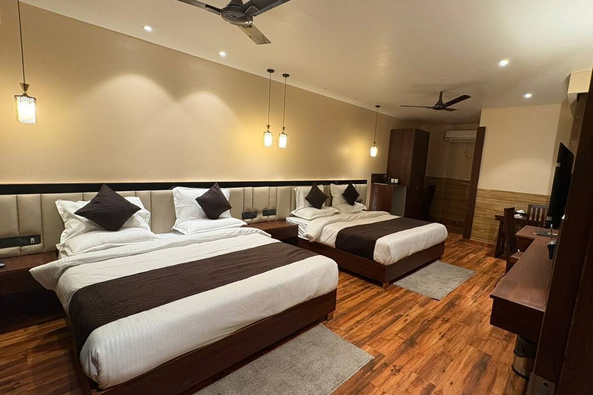 Habitación de hotel con dos camas, un escritorio, una silla, un televisor y un ventilador de techo.