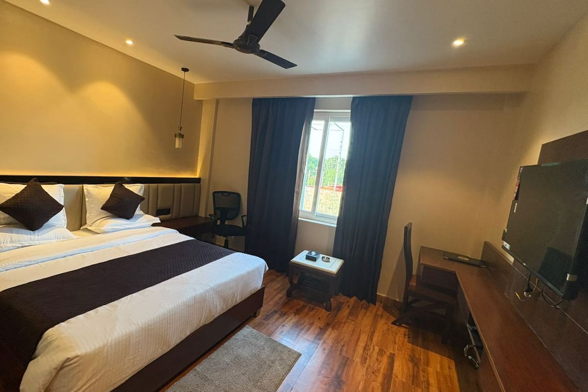 Una habitación de hotel moderna con una cama grande, un escritorio, un televisor y un ventilador de techo.
