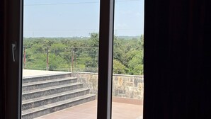 Vista desde una ventana con un muro de piedra y escalones que llevan a un balcón.