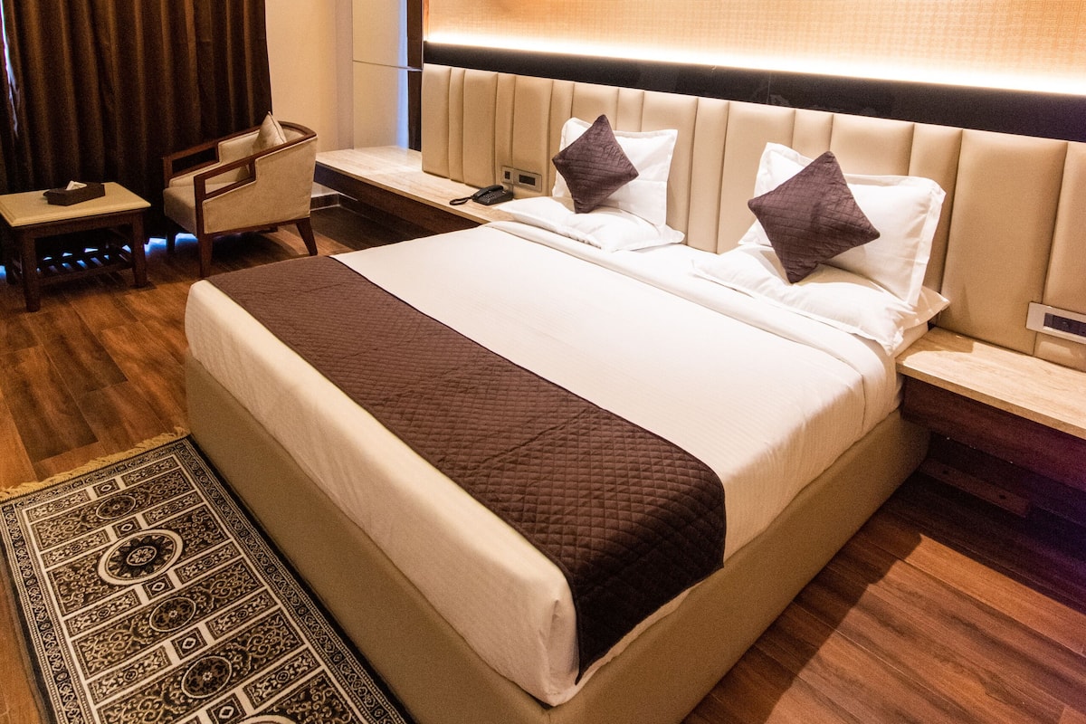 Habitación de hotel moderna con una cama grande, mesitas de noche, un escritorio y una alfombra estampada.