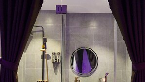 A modern bathroom with a glass shower enclosure, a round mirror, a white sink, and a toilet. - Punita Hotel (Da Nang)