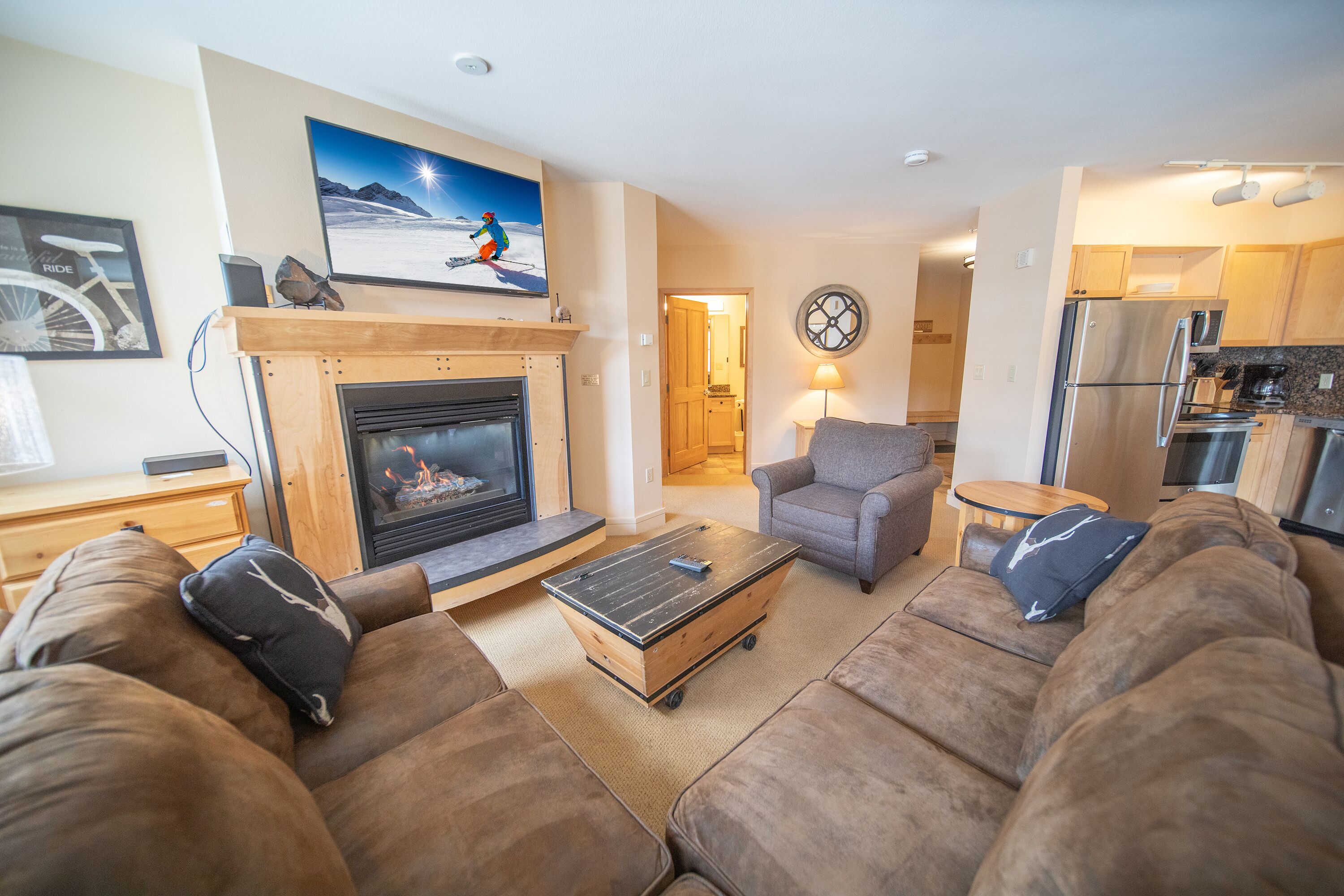 A living room with a fireplace, sofa, coffee table, and a television mounted above the fireplace.