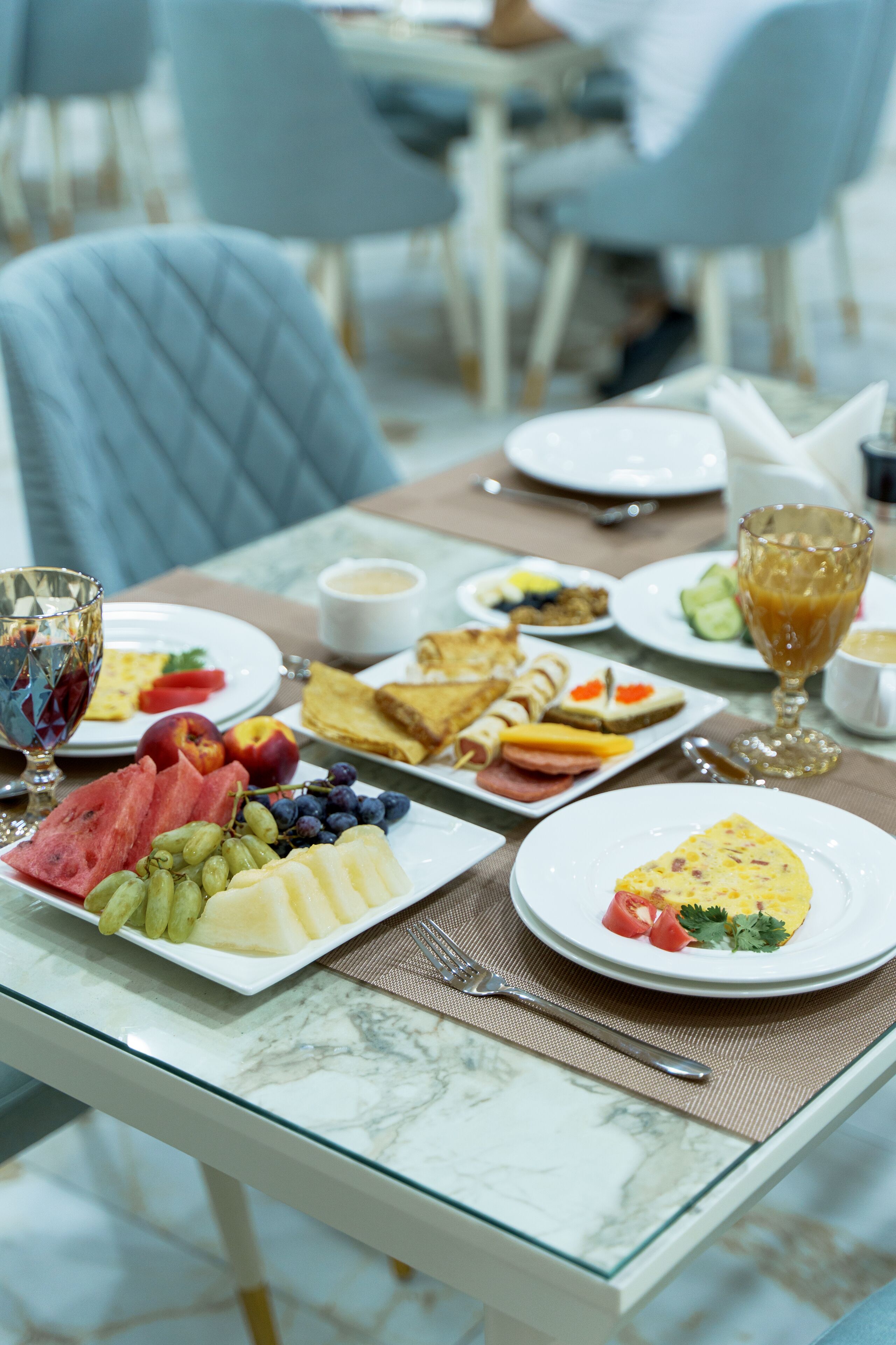 Una mesa de desayuno con diferentes alimentos, como frutas, queso y tostadas.