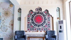 Una habitación con dos sillones tapizados, una mesa de madera y una pared decorativa con diseños elaborados.