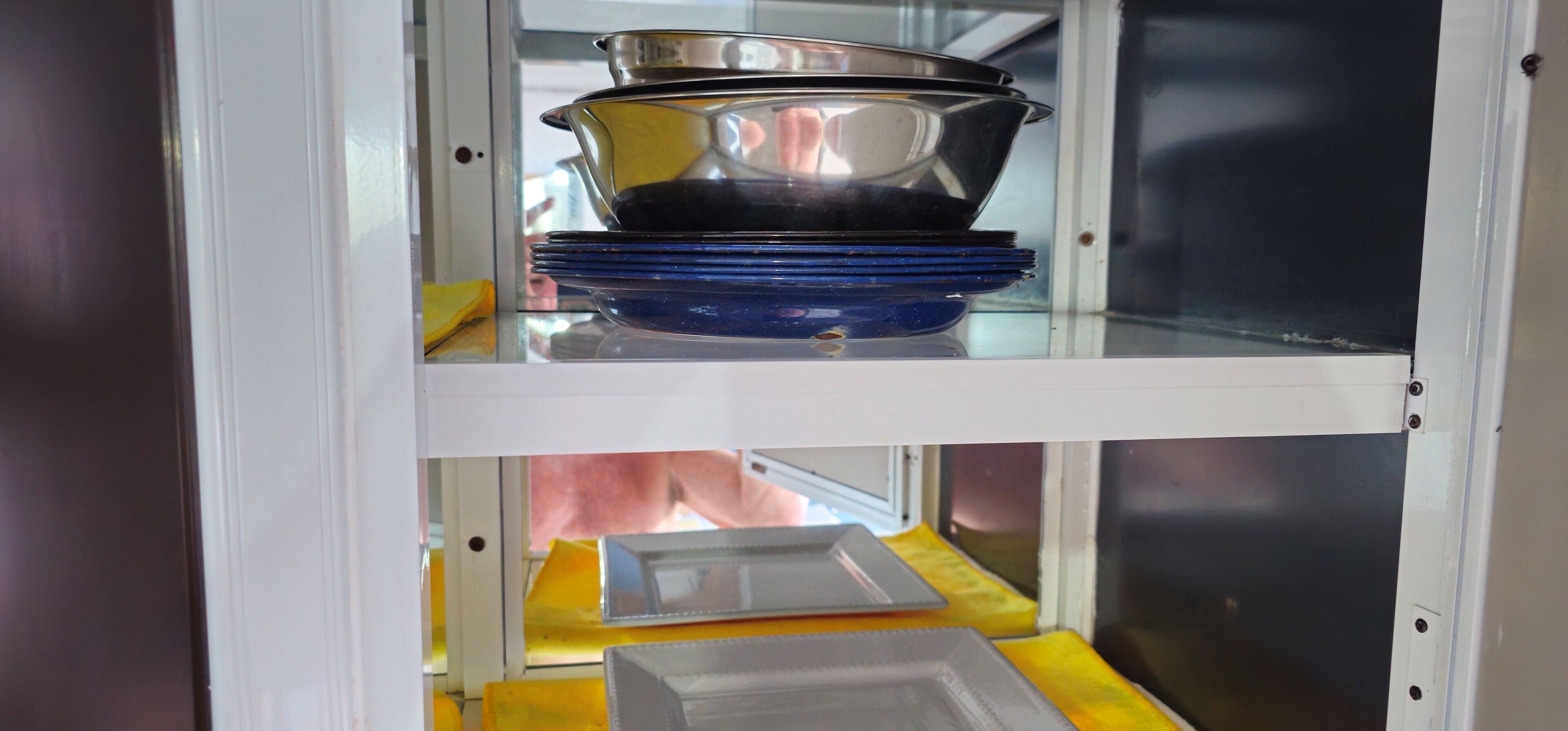 A kitchen cabinet with stacked dishes and a microwave.