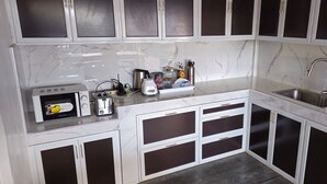 A kitchen with white marble countertops, a built-in microwave, a toaster, and a sink. - MyFantasyResort.com Room A - Occupancy 2-3 Guests (Lemery Ph)