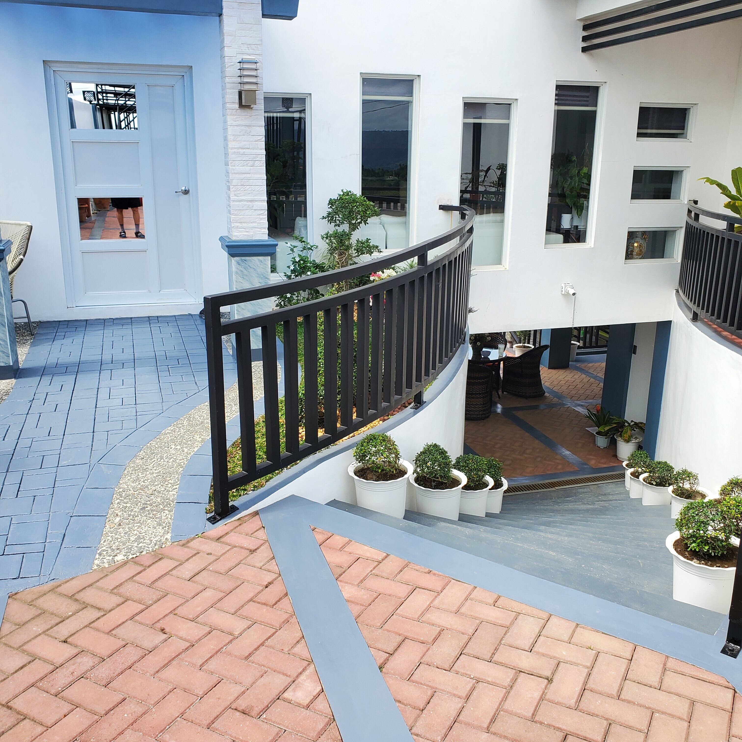 A modern building with a white exterior, a black railing, and potted plants.