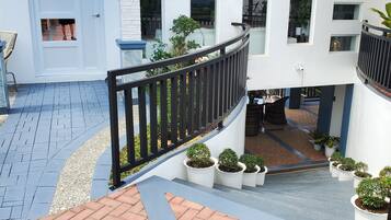 A modern building with a white exterior, a black railing, and potted plants.