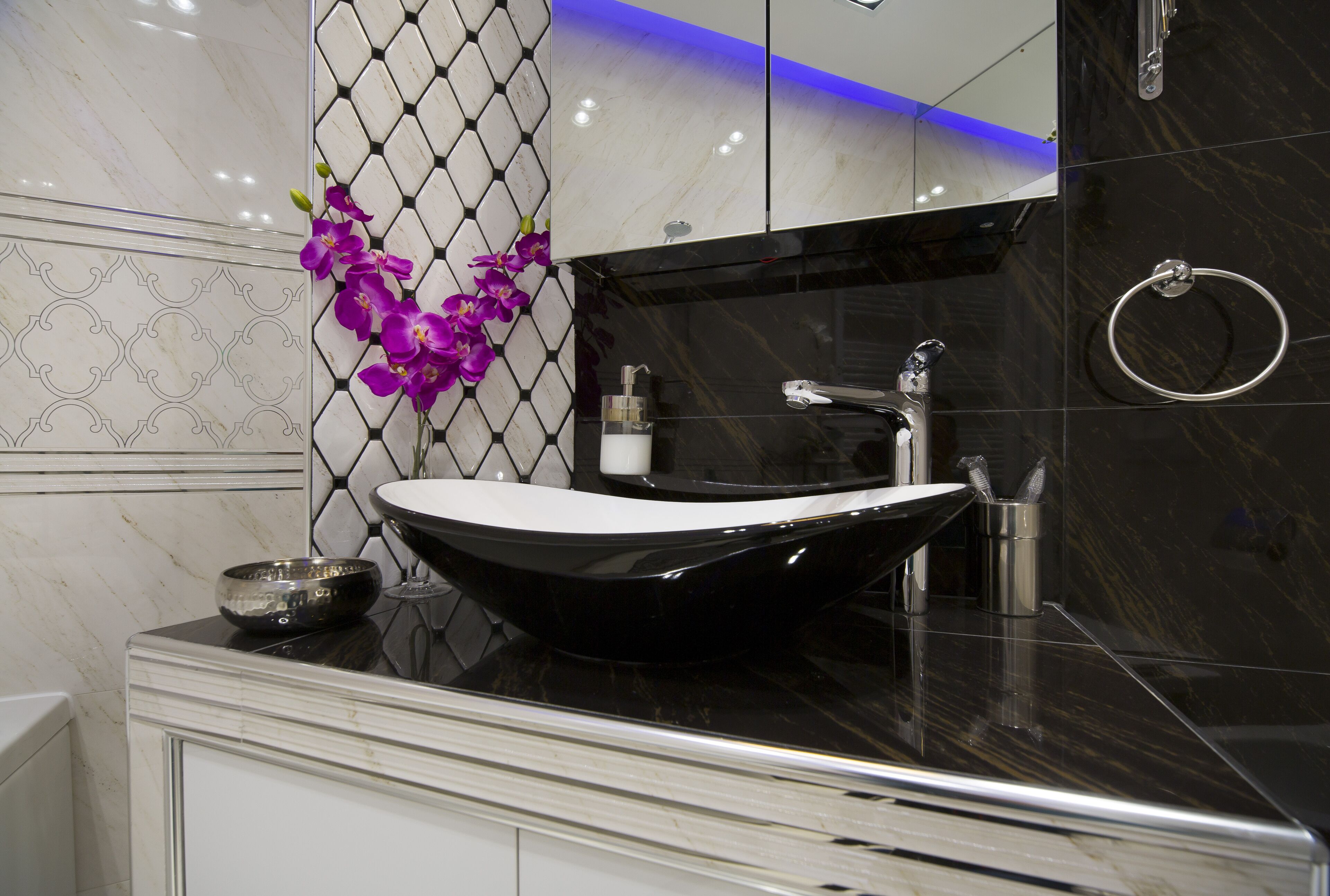 A modern bathroom with a black vessel sink, a mirror, and a towel ring.