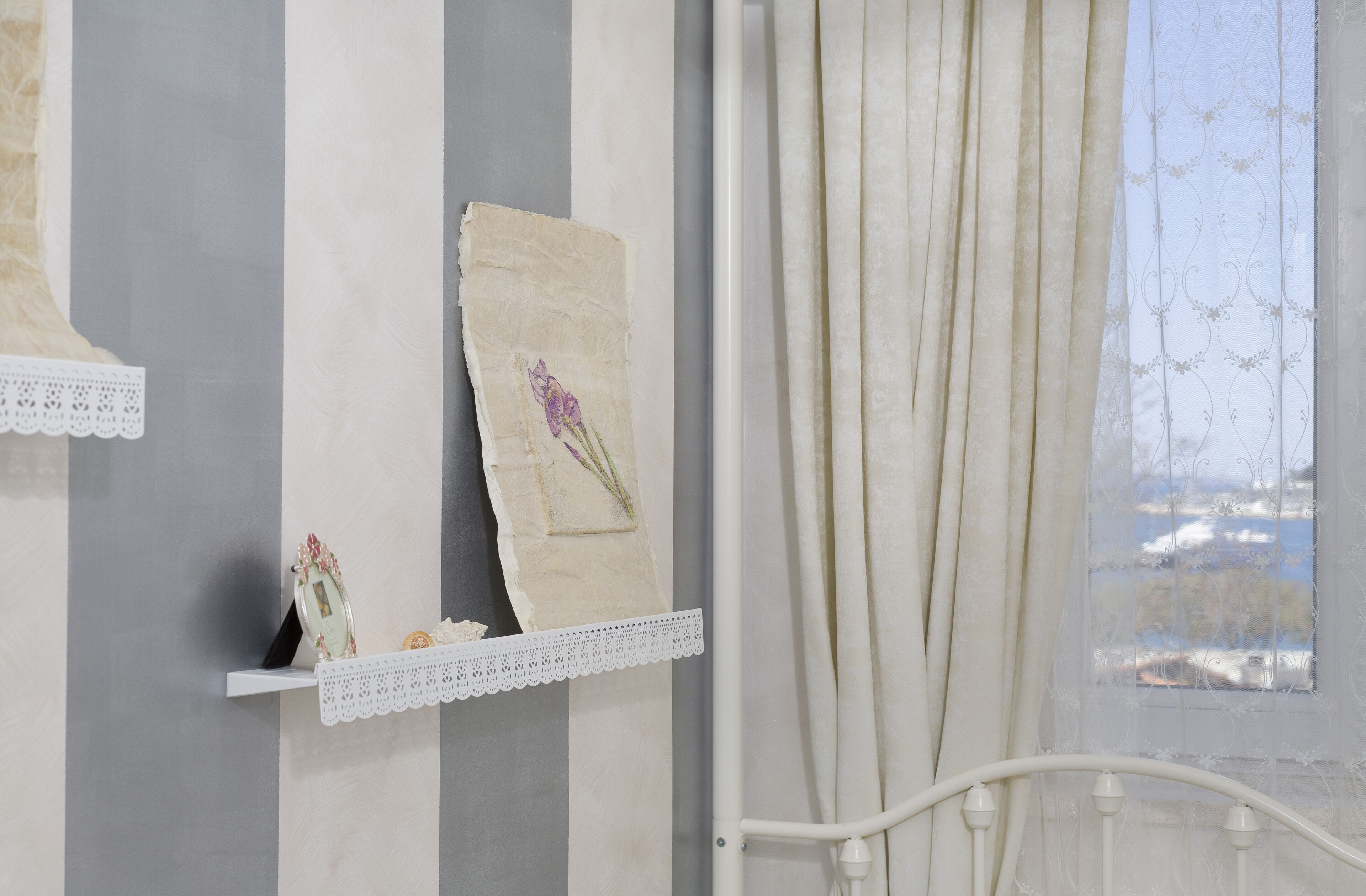 A room with a bed, a shelf with decorative items, and a window with curtains.